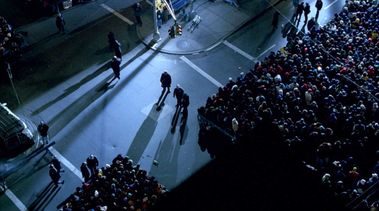 a group of people standing on a street next to a crowd of people