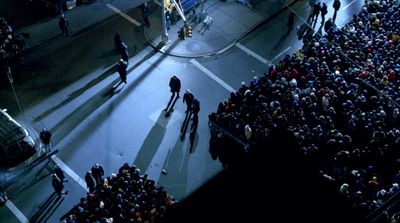 a group of people standing on a street next to a crowd of people