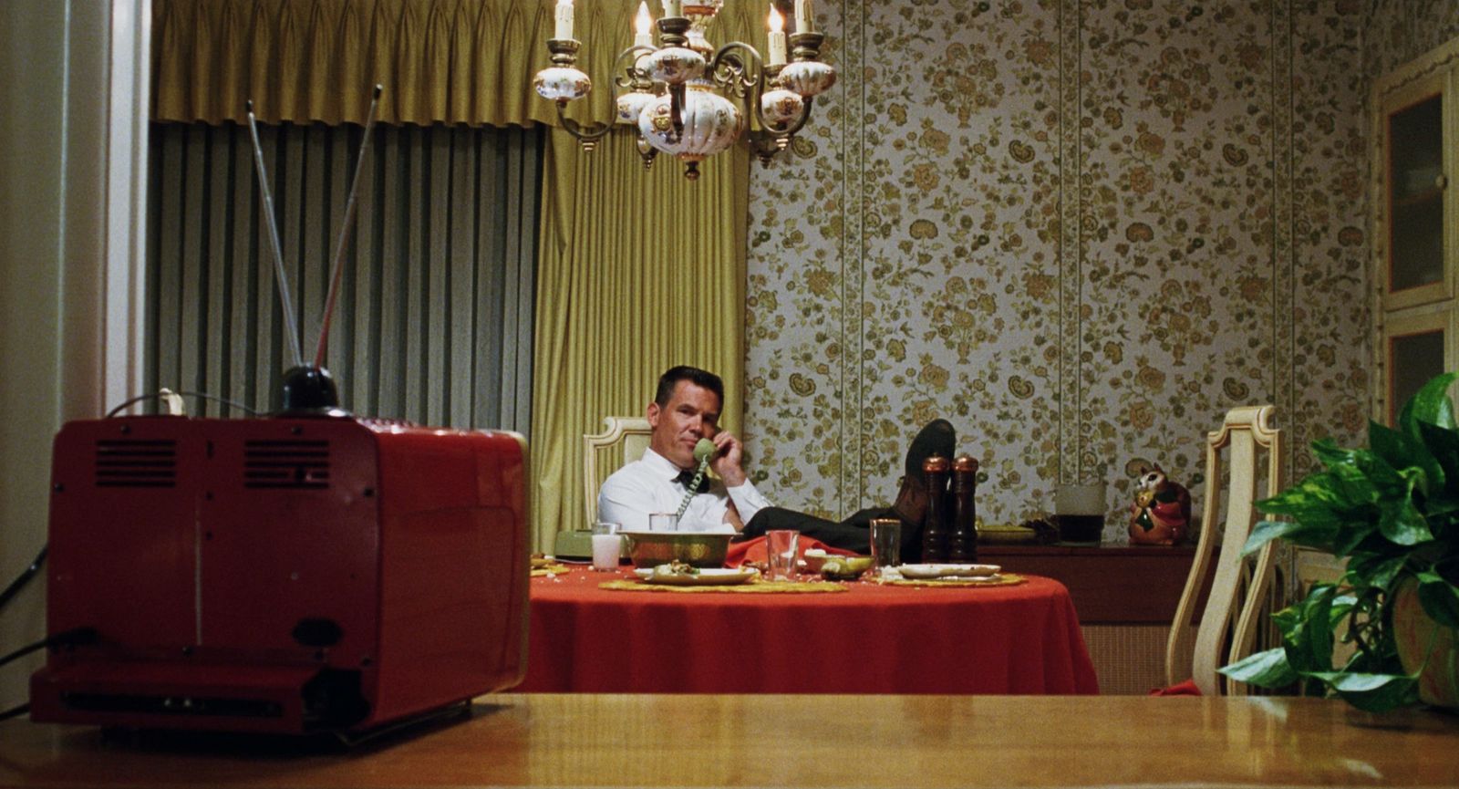 a man sitting at a table talking on a cell phone