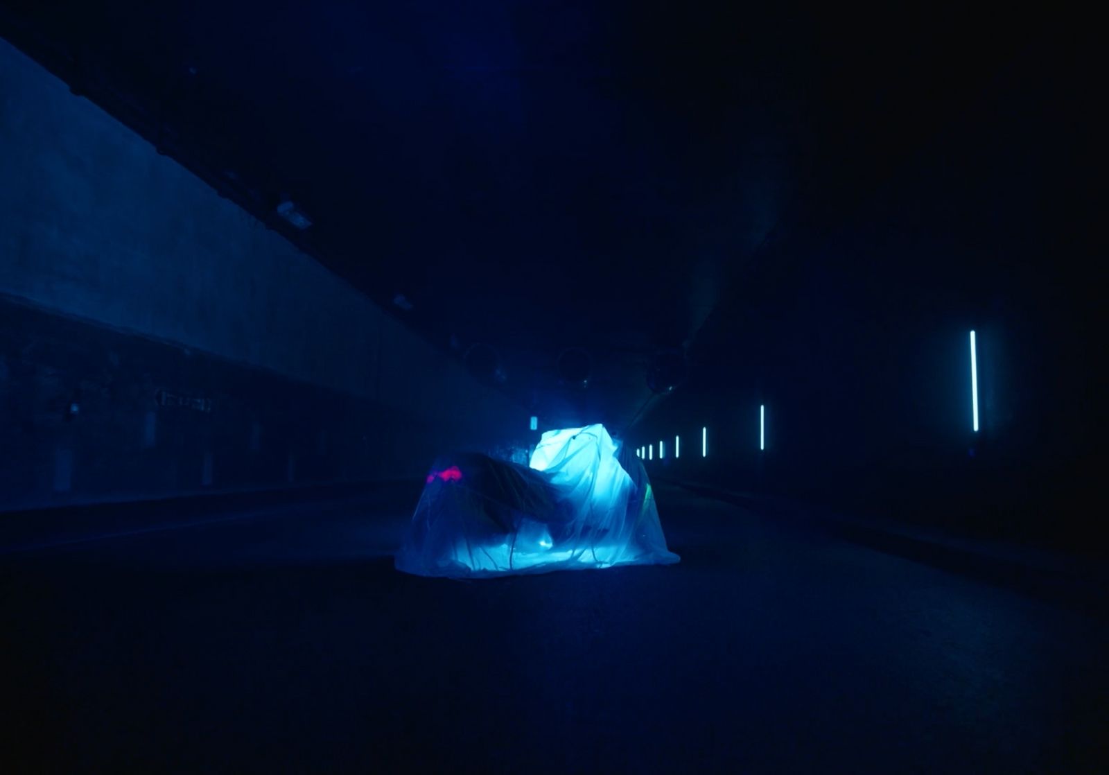 a woman in a white dress standing in a dark tunnel