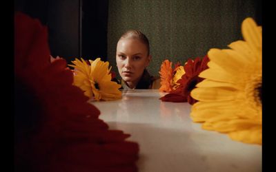 a woman sitting at a table with flowers in front of her