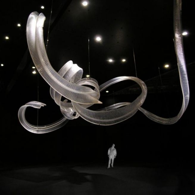 a man standing in front of a sculpture in a dark room