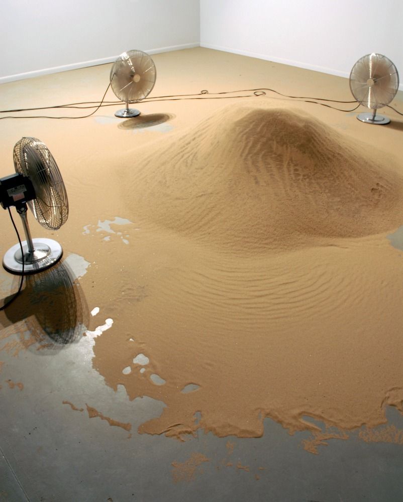 a room with a lot of sand and some fans