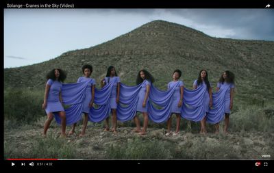 a group of women in blue dresses standing in front of a mountain