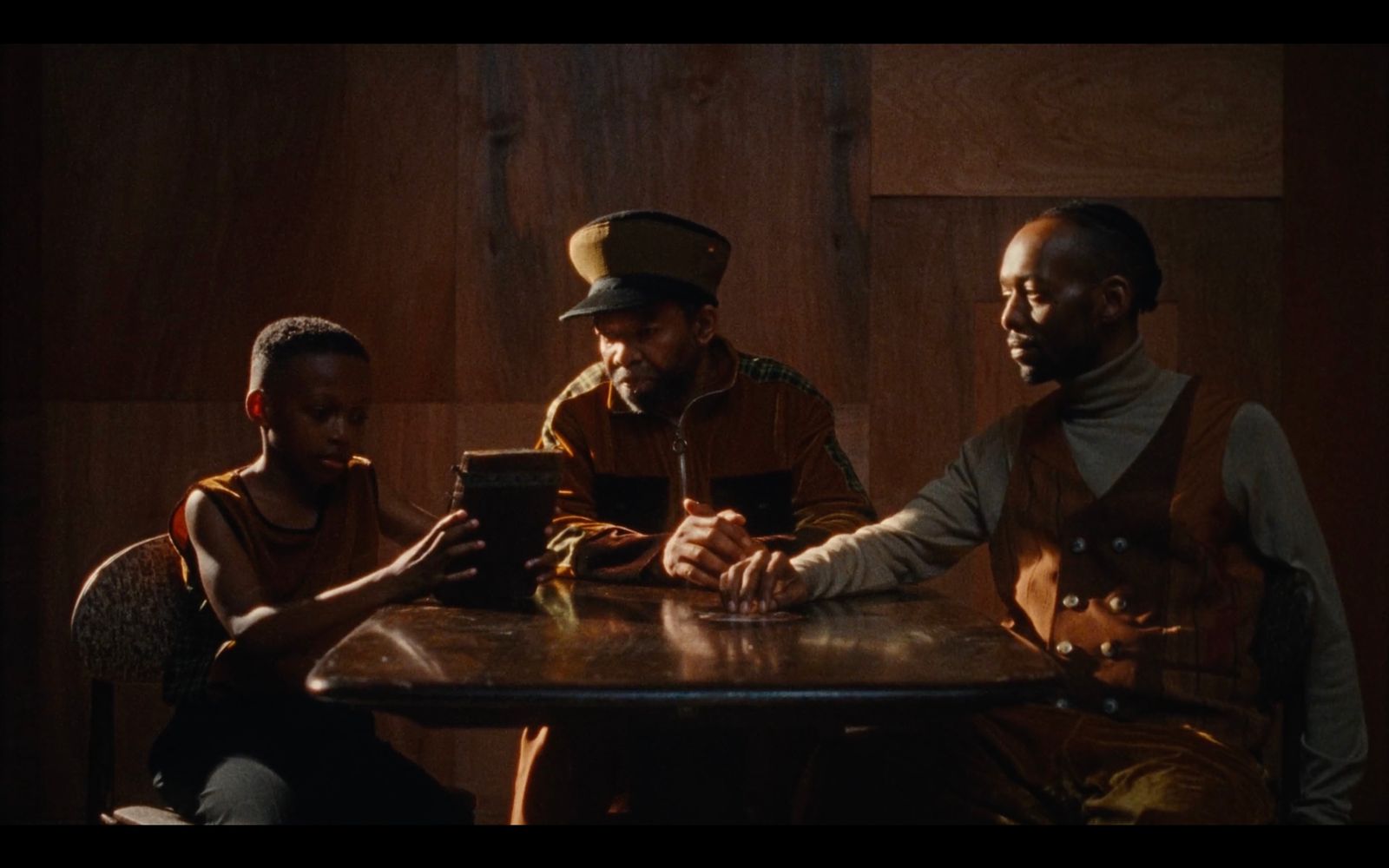 three people sitting at a table looking at a tablet