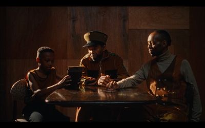 three people sitting at a table looking at a tablet