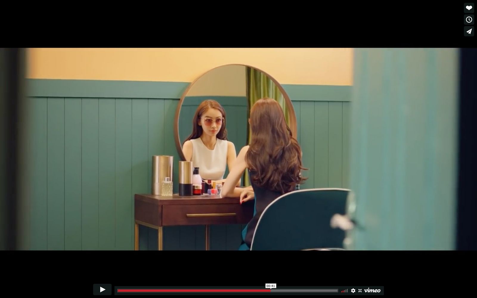 a woman sitting at a vanity in front of a mirror