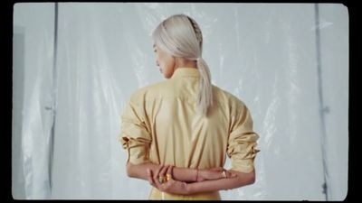 a woman in a yellow dress standing in front of a white backdrop