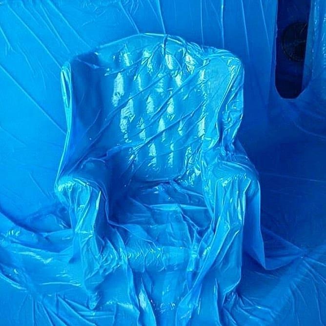 a blue chair covered in plastic sitting in a room