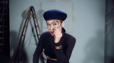 a woman in a black shirt and a hat with a magnifying glass