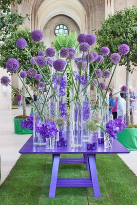 a purple table topped with vases filled with purple flowers