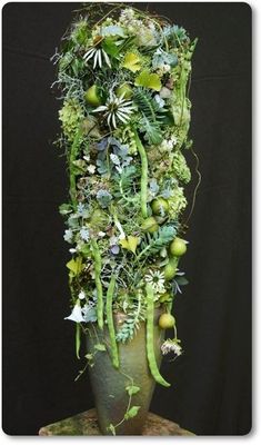 a tall vase filled with lots of green plants