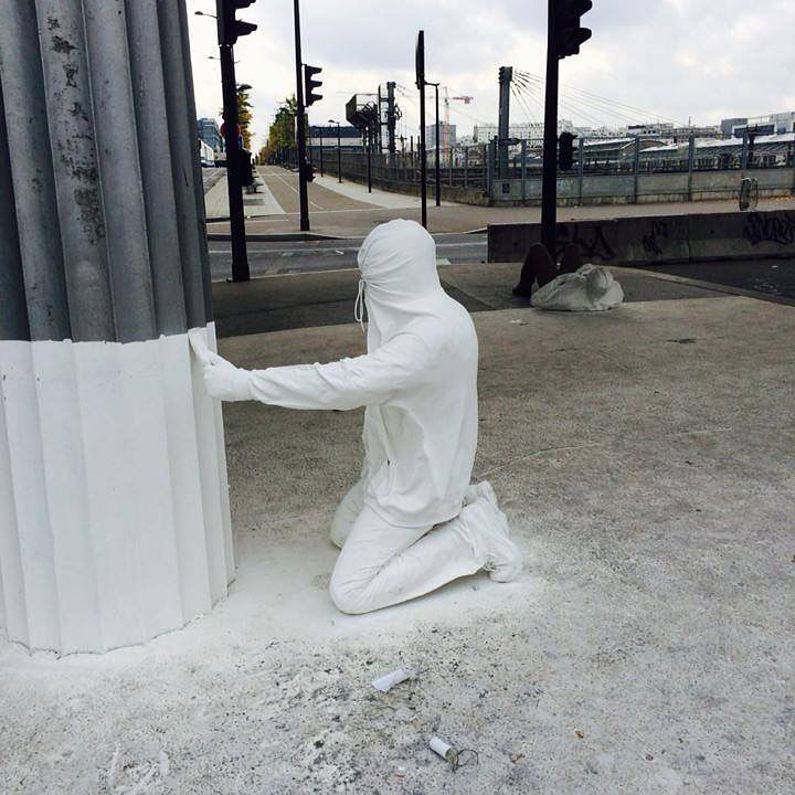 a person in a white outfit kneeling next to a pole