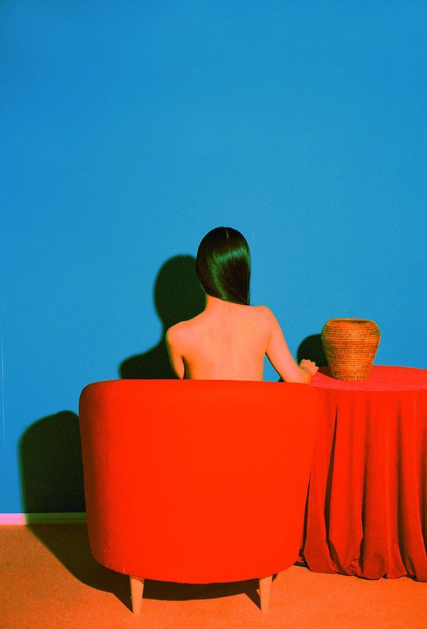 a woman sitting on a red chair in front of a blue wall