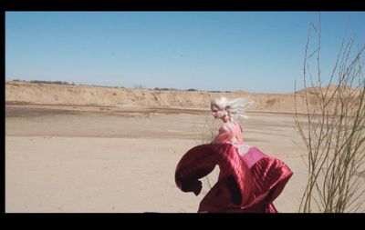 a woman in a red dress standing on a beach