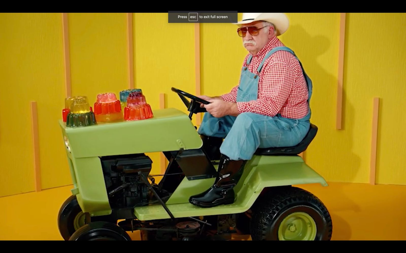 a man sitting on top of a green lawn mower