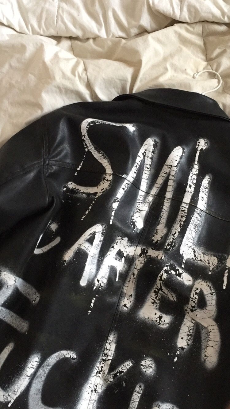 a black leather jacket with graffiti written on it