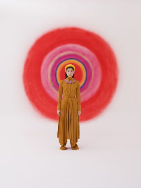 a woman standing in front of a red and pink circle