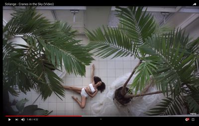 a woman laying on a tiled floor next to a palm tree