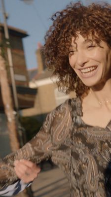 a woman with curly hair is smiling at the camera