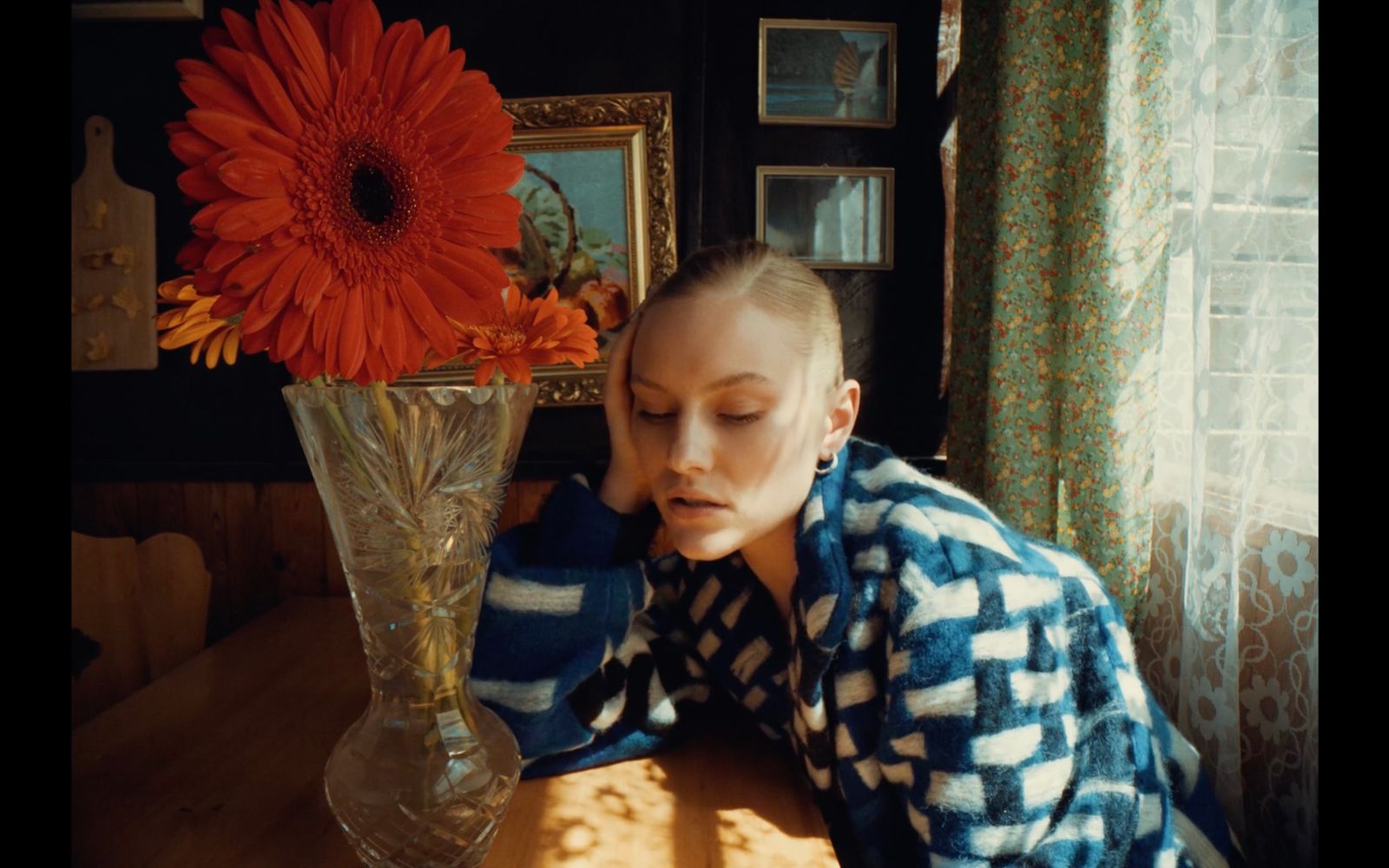 a woman sitting in front of a vase with a flower in it