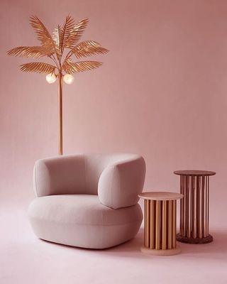 a pink room with a white chair and a palm tree