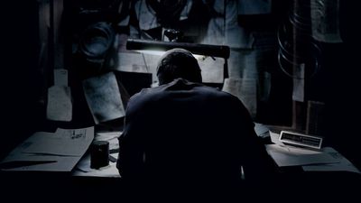 a man sitting at a desk in a dark room