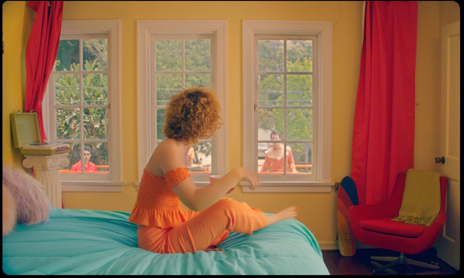 a woman sitting on a bed looking out a window