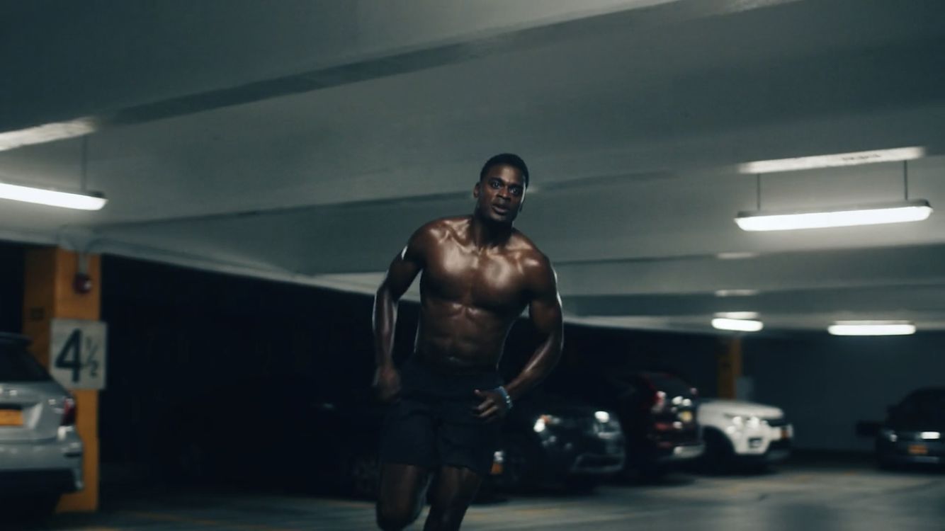 a shirtless man running in a parking garage