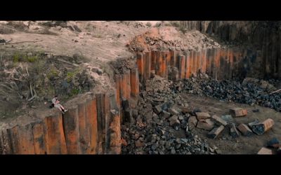 a man standing on top of a cliff next to a pile of rocks