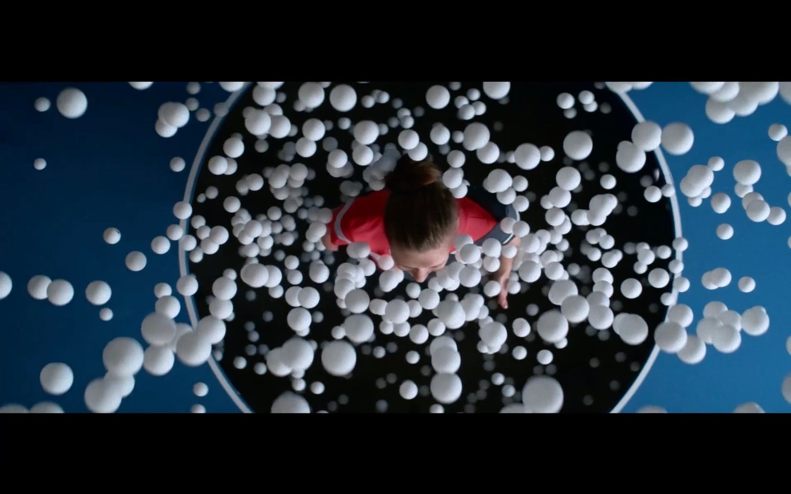 a person in a red shirt is surrounded by white balls