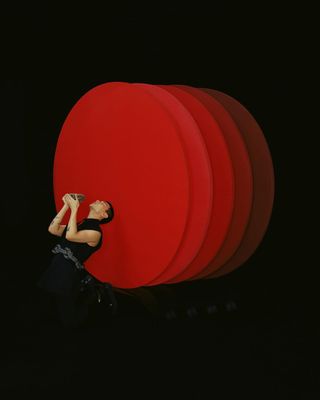 a woman standing in front of a large red object