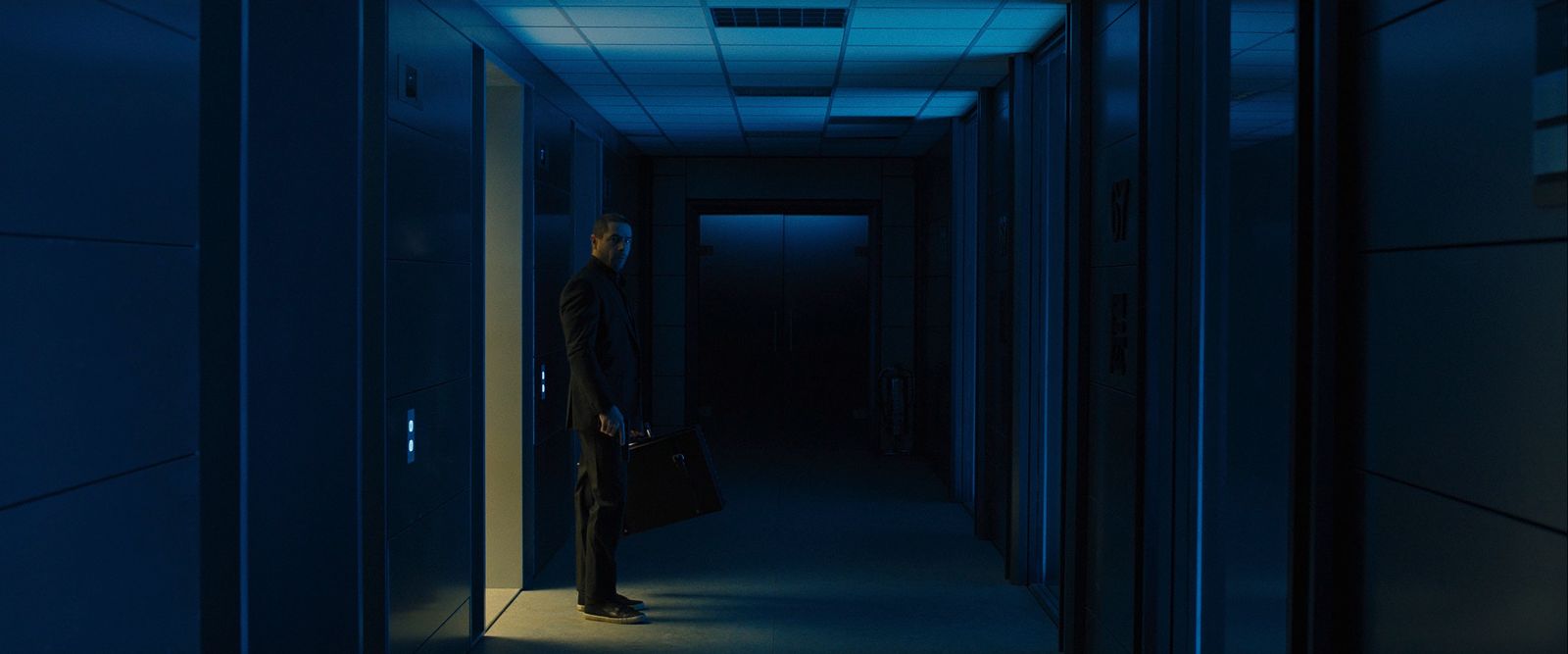 a man standing in a dark hallway with a briefcase