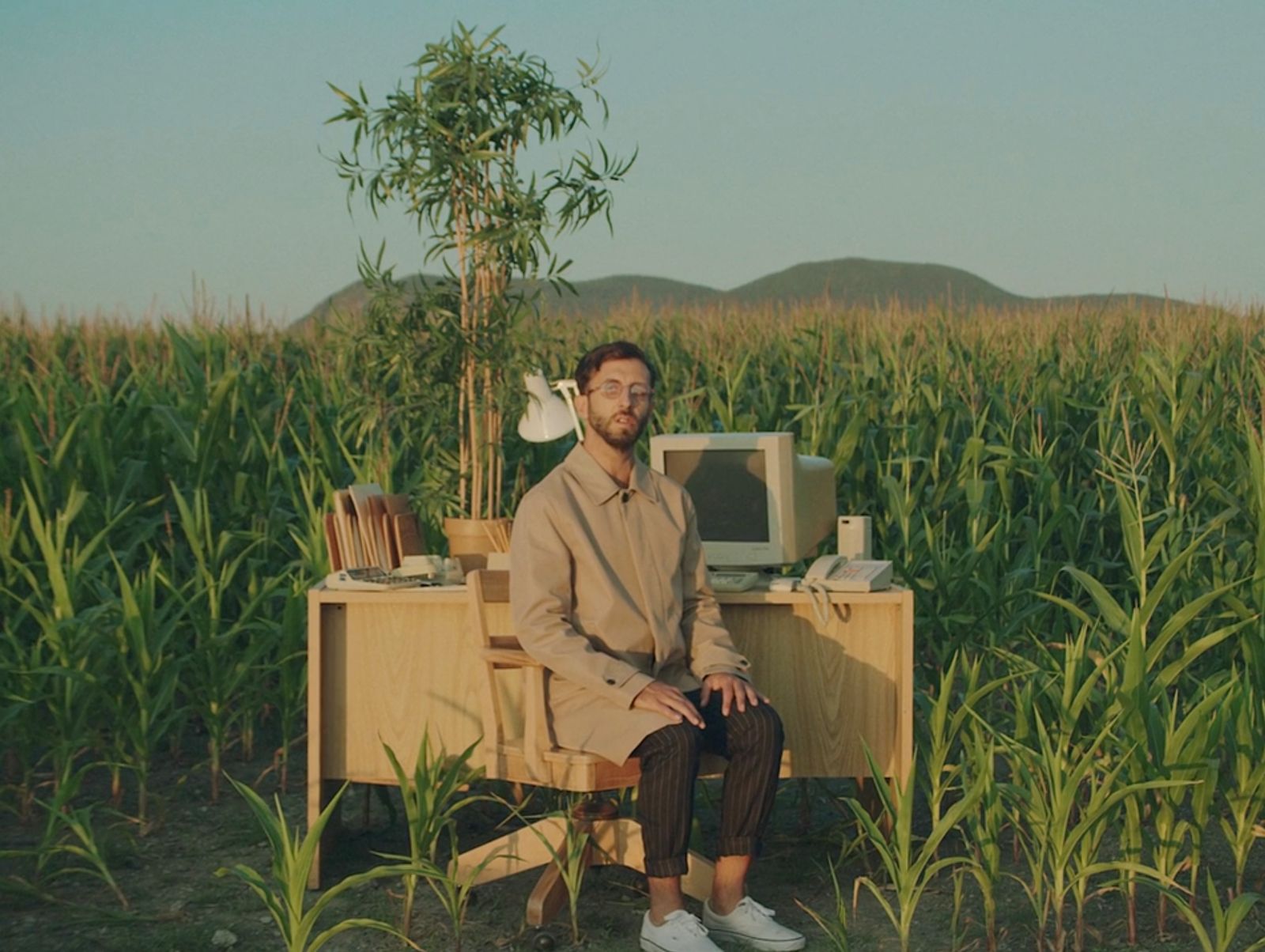 a man sitting on a desk in a corn field