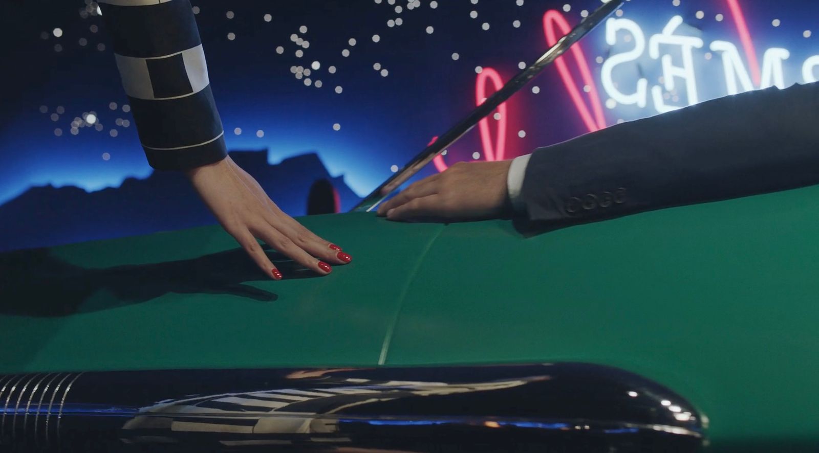 a woman's hand on the hood of a green car