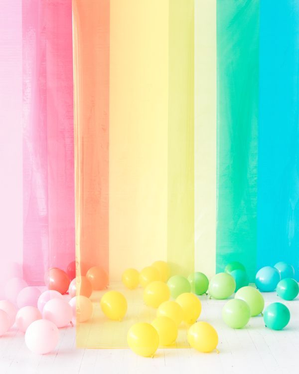 a group of balloons sitting in front of a rainbow colored wall