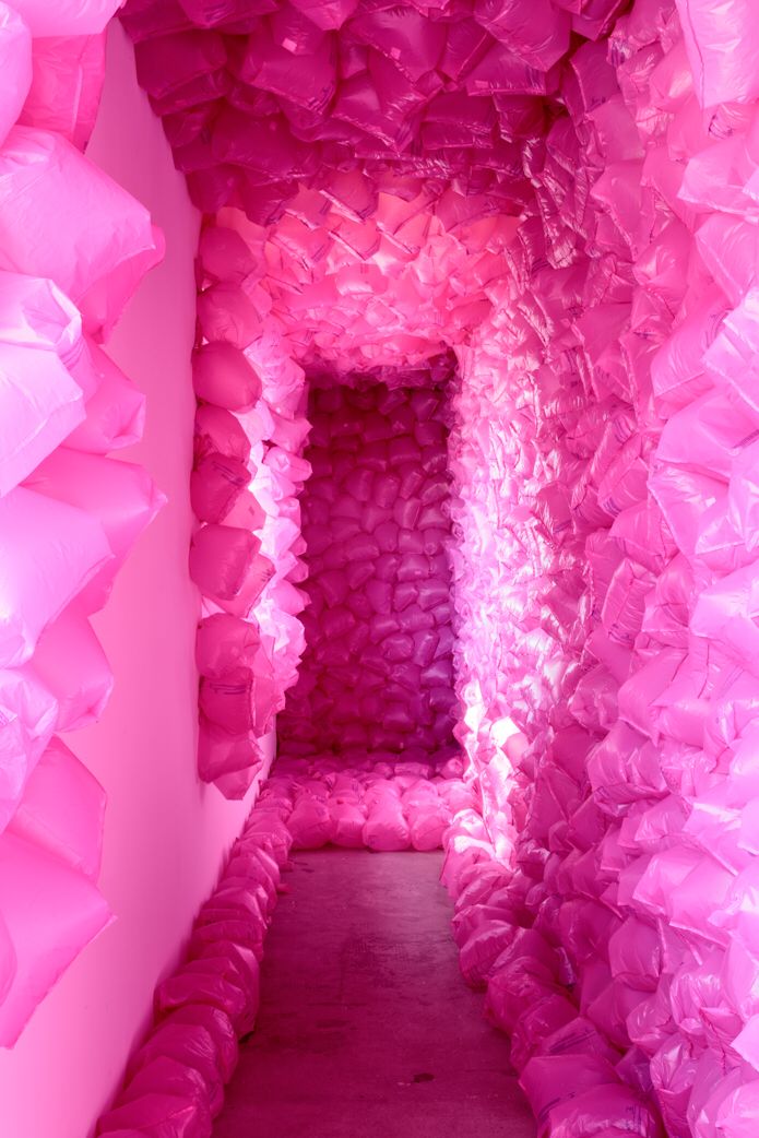 a tunnel of pink plastic bags in a room