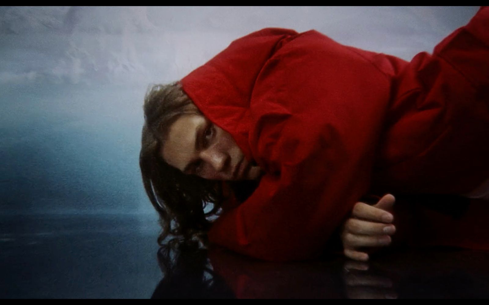 a woman in a red jacket laying on the ground