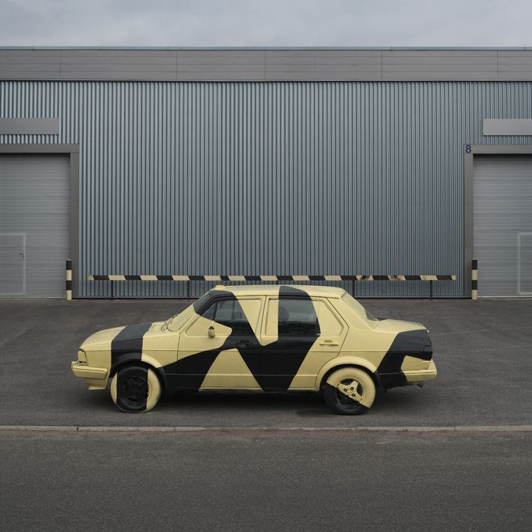 a yellow and black car parked in front of a building