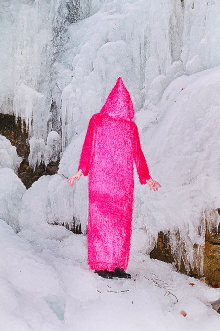 a person in a pink bathrobe standing in the snow