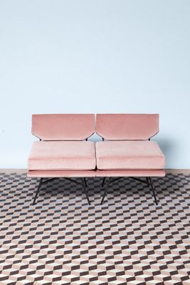 a pink couch sitting on top of a checkered floor