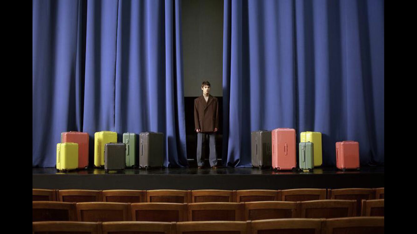 a man standing in front of a row of suitcases