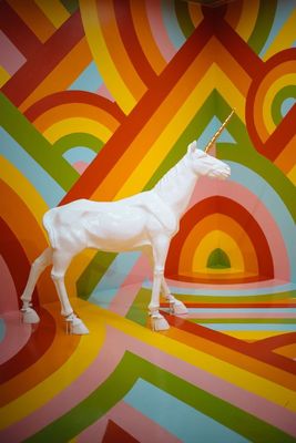 a white unicorn statue standing in front of a colorful wall