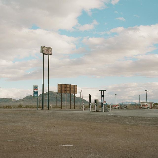 an empty parking lot with a gas station in the background