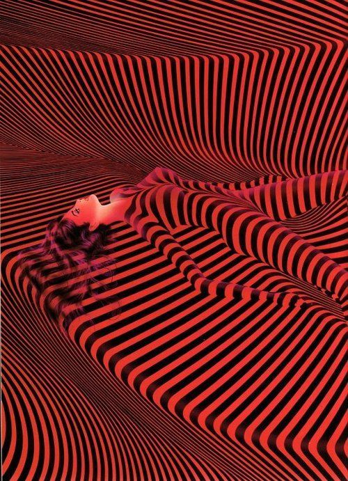 a woman laying on top of a bed covered in red and black stripes