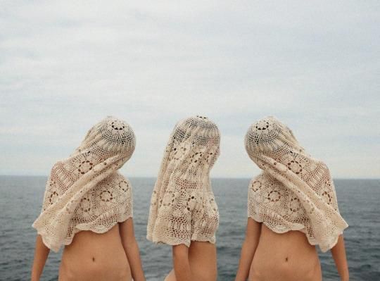 two women with lacy shawls on their heads looking out at the ocean