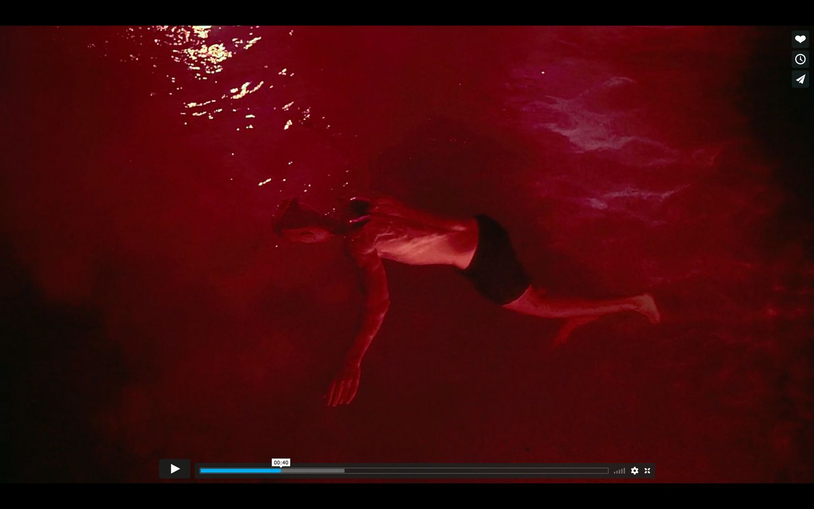 a man swimming in the water with a red background