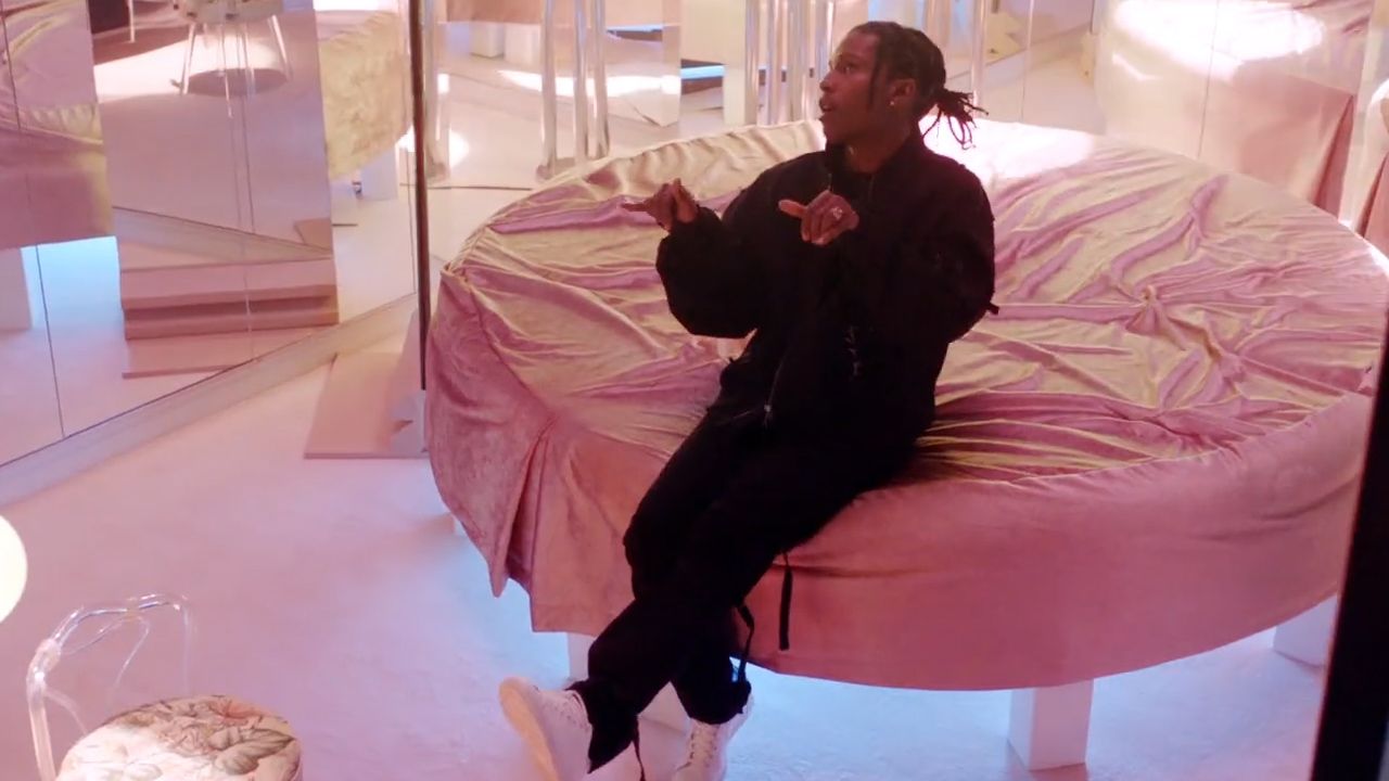 a man sitting on top of a pink round bed