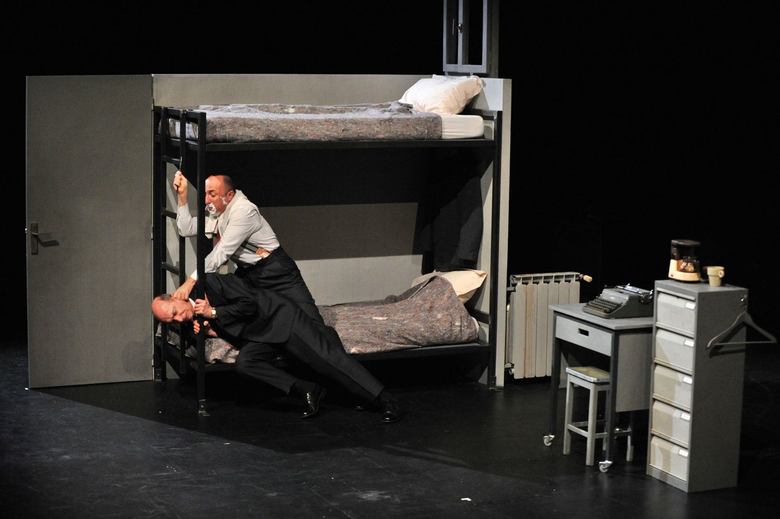 a couple of men sitting on top of a bunk bed