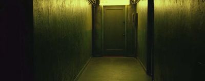 a dark hallway with a door and a light at the end